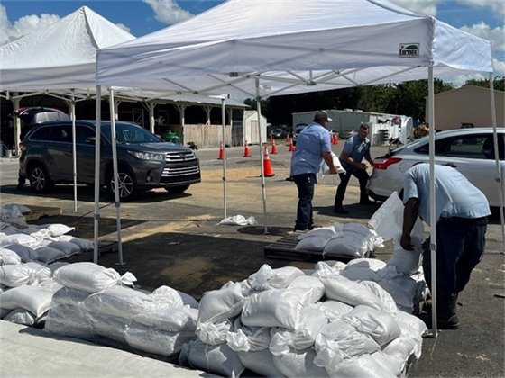 A white tent with sandbags and people loading them into a truck