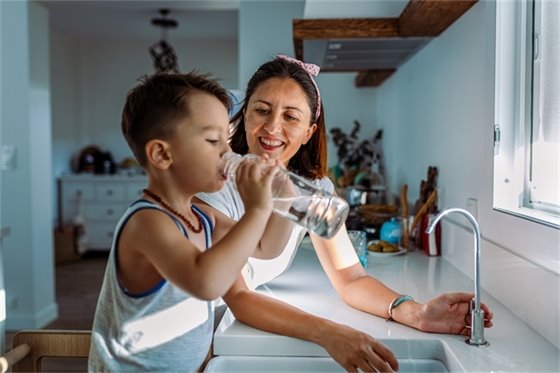 Young Kid Drinking Water and Mom Next to Him 